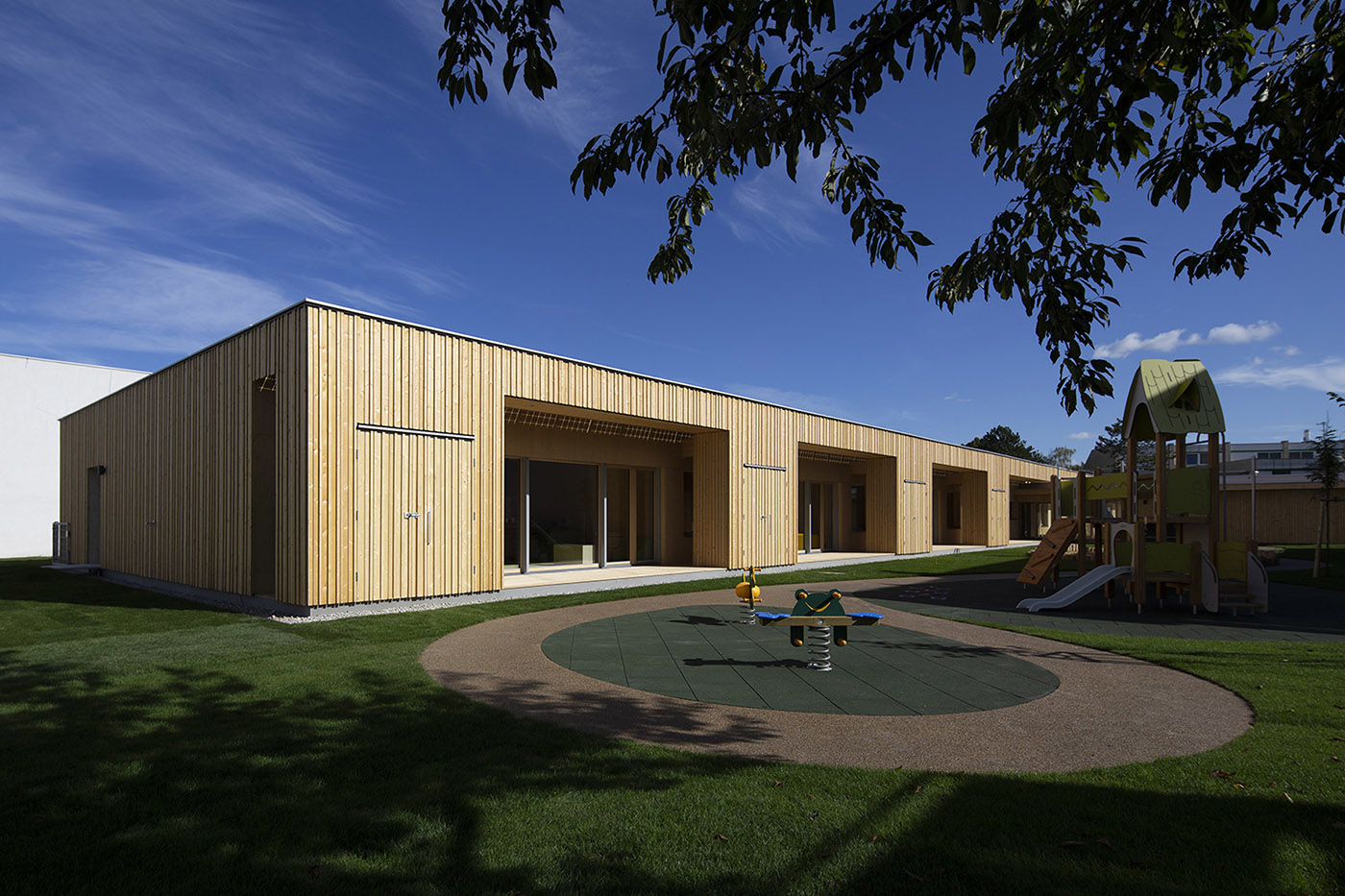 Kindergarten built with solid wood. Single-storey building in a heterogeneous environment