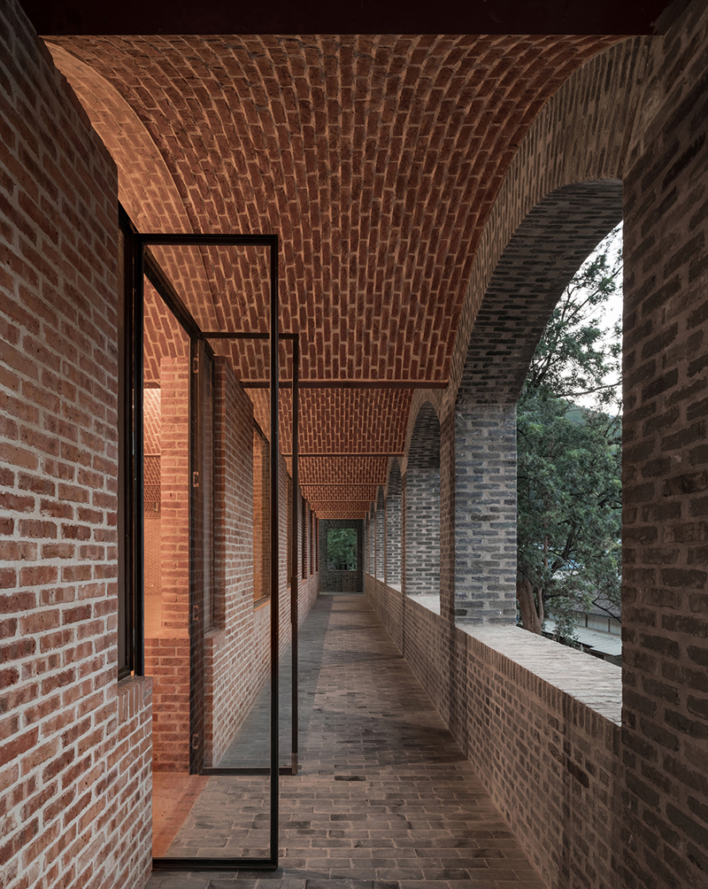 Briques, cours, arbres luxuriants. Rénovation d'un bâtiment datant des années 80