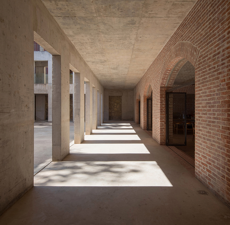 Briques, cours, arbres luxuriants. Rénovation d'un bâtiment datant des années 80