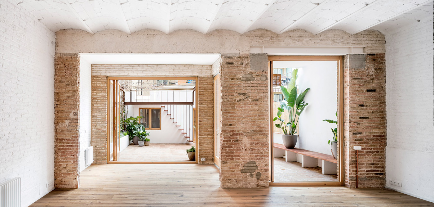 Galerie perméable entre la route et la cour intérieure. La maison sombre laisse entrer la lumière