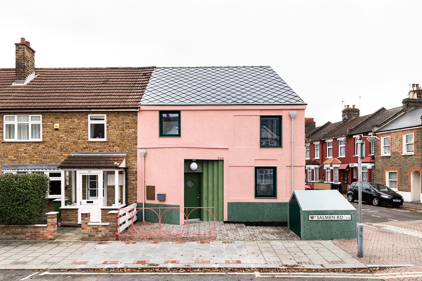 House with pink and green plaster. The colours break the connection with the traditional design