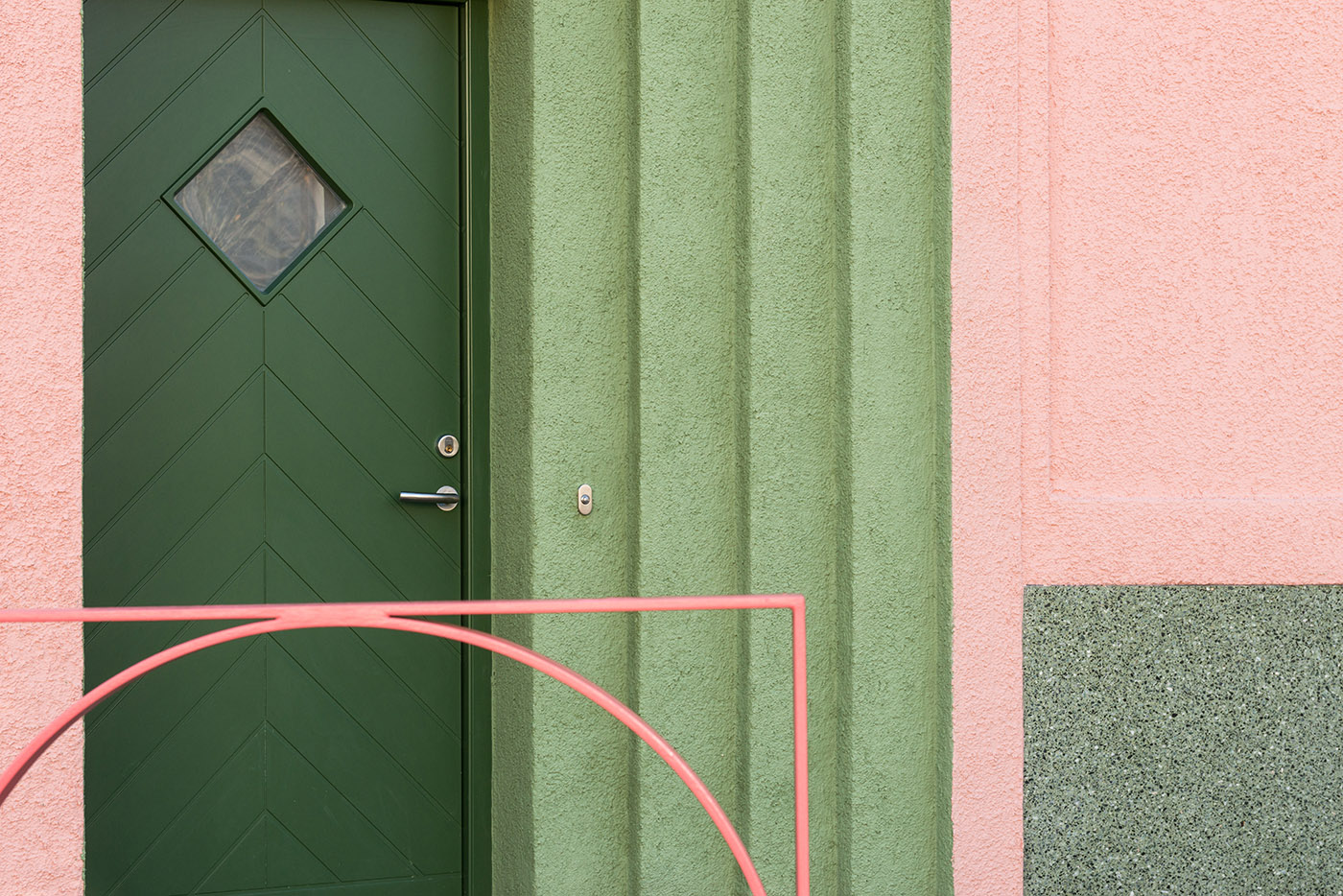 House with pink and green plaster. The colours break the connection with the traditional design