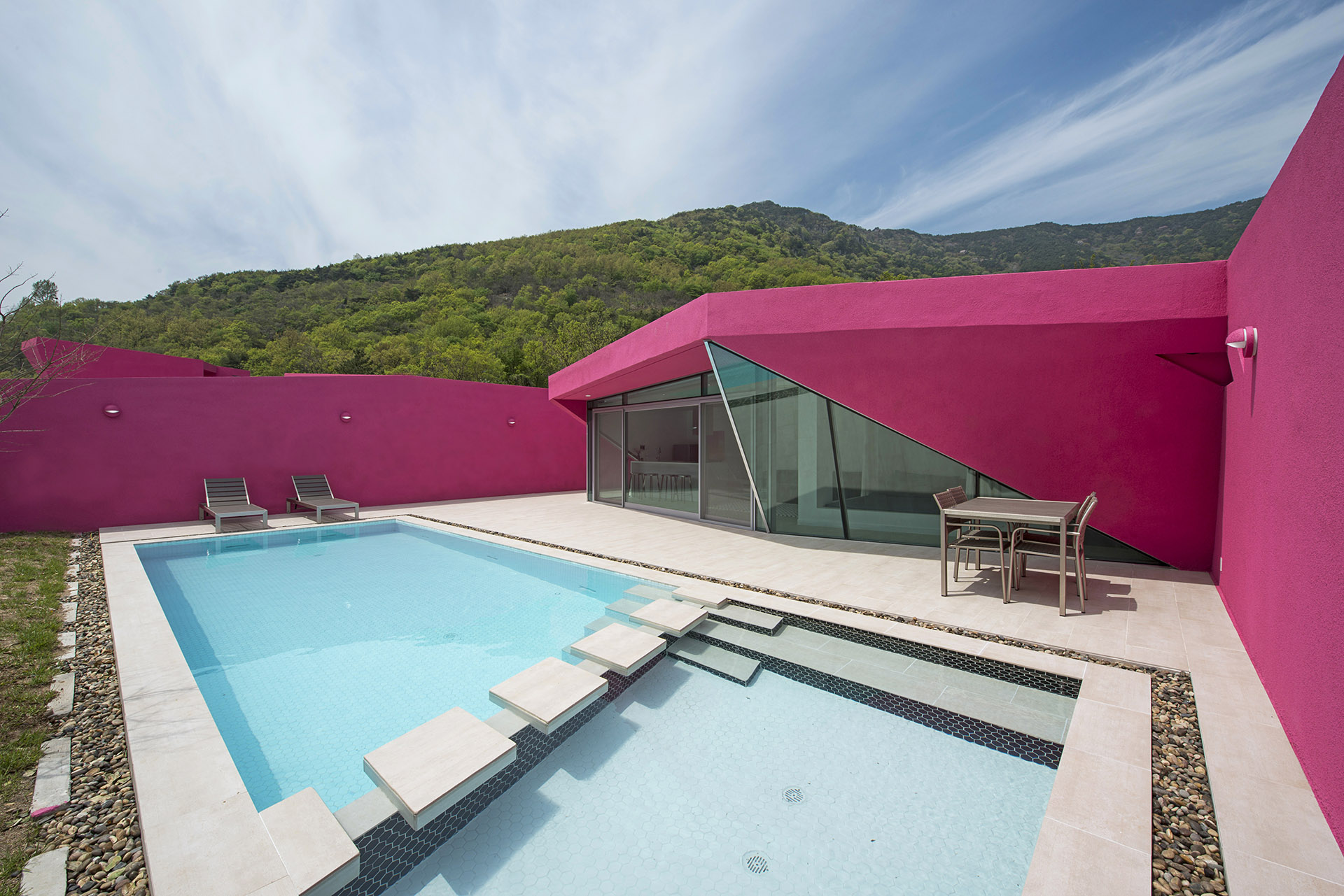 Rose-toned villa among verdant hills. Walls frame the spectacular view