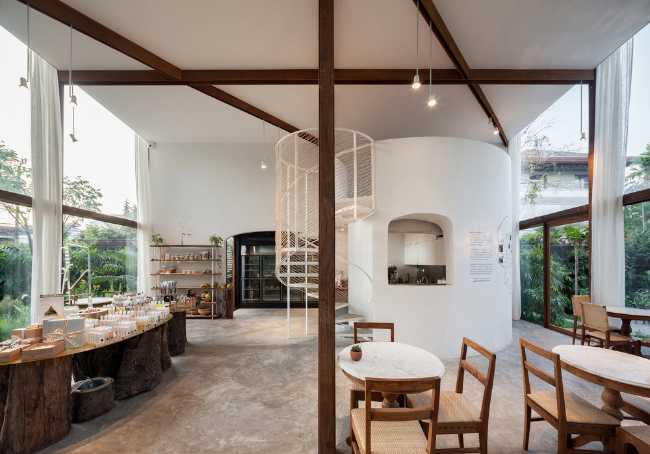 Showroom en verre avec structure en bois. La transparence révèle un luxuriant jardin environnant