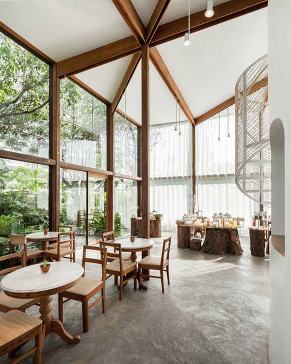 Showroom en verre avec structure en bois. La transparence révèle un luxuriant jardin environnant