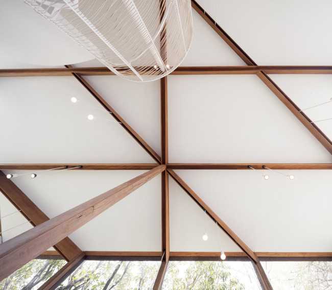 Showroom en verre avec structure en bois. La transparence révèle un luxuriant jardin environnant