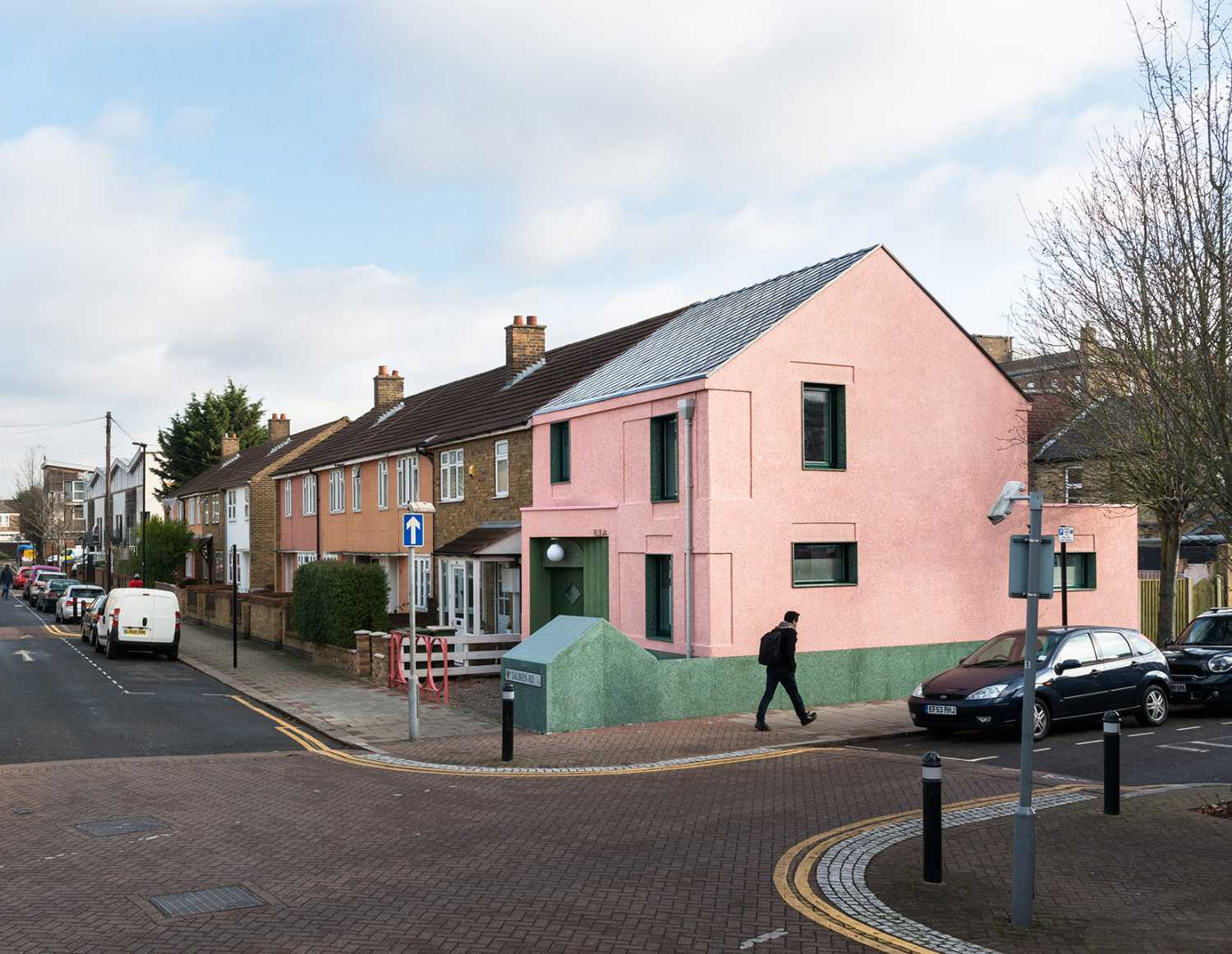 House with pink and green plaster. The colours break the connection with the traditional design