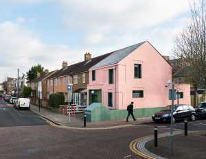 House with pink and green plaster. The colours break the connection with the traditional design