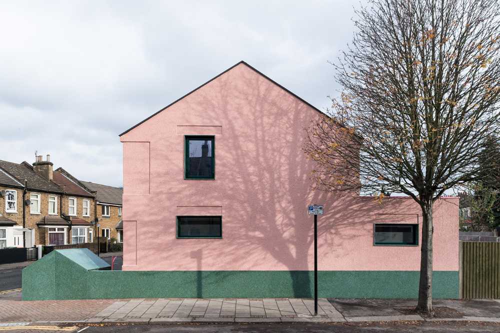 House with pink and green plaster. The colours break the connection with the traditional design