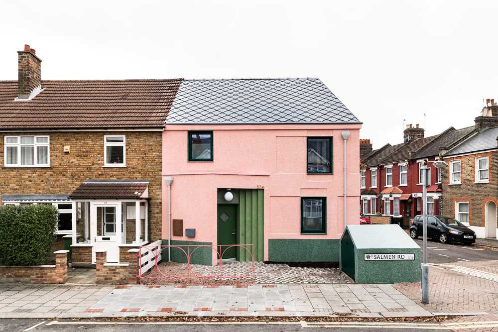 House with pink and green plaster. The colours break the connection with the traditional design