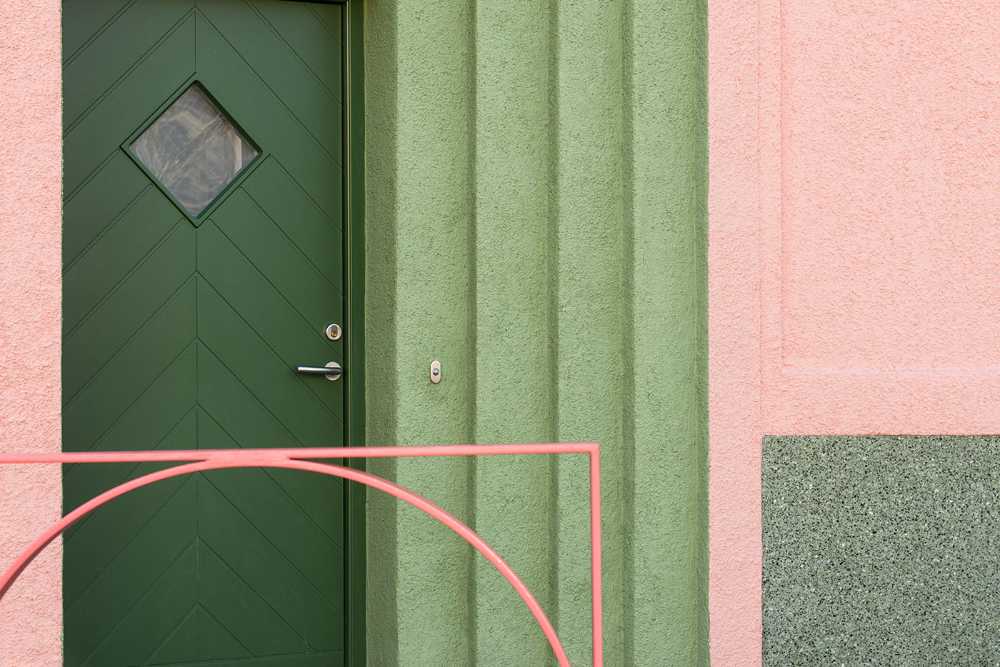 House with pink and green plaster. The colours break the connection with the traditional design