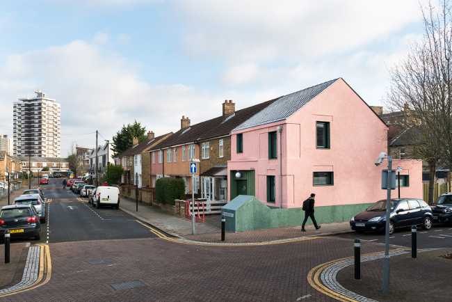 House with pink and green plaster. The colours break the connection with the traditional design