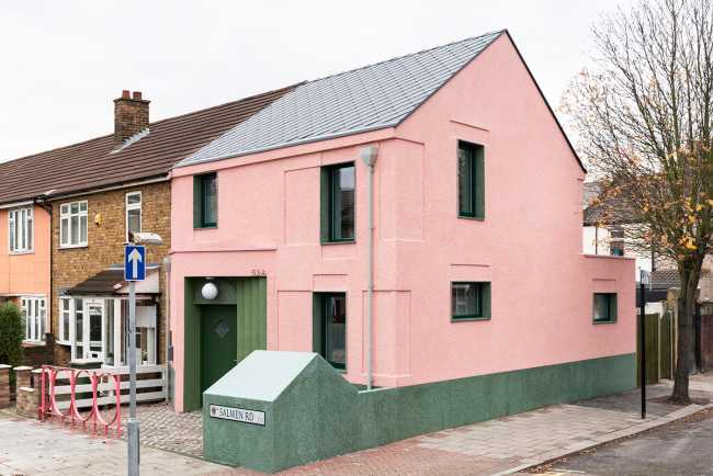 House with pink and green plaster. The colours break the connection with the traditional design
