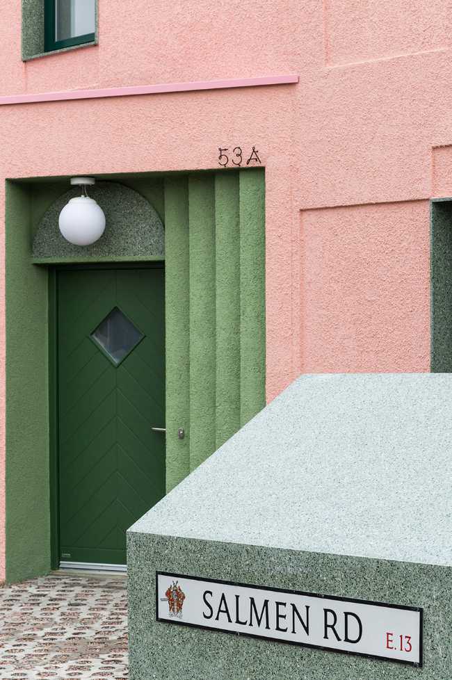 House with pink and green plaster. The colours break the connection with the traditional design