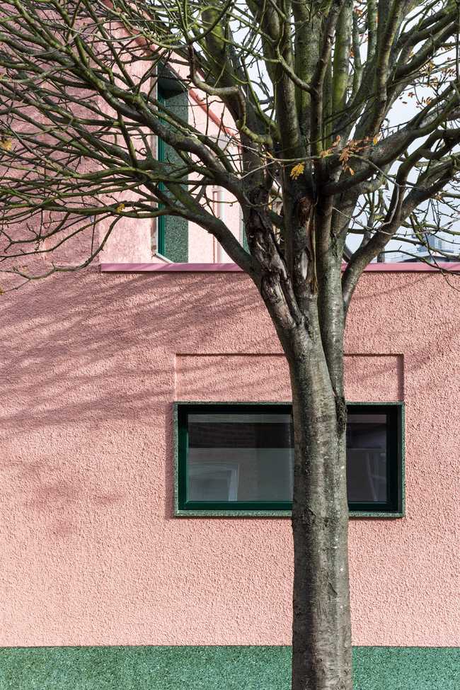 House with pink and green plaster. The colours break the connection with the traditional design