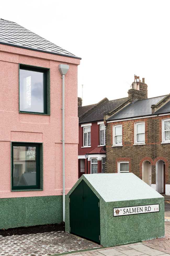 House with pink and green plaster. The colours break the connection with the traditional design