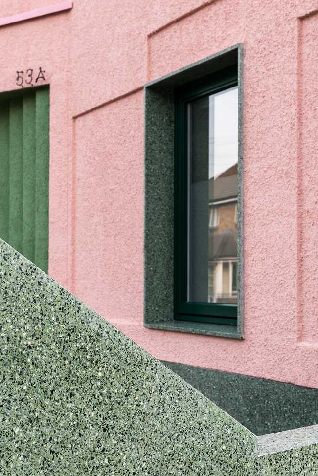 House with pink and green plaster. The colours break the connection with the traditional design