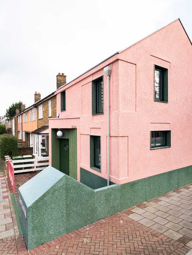 House with pink and green plaster. The colours break the connection with the traditional design