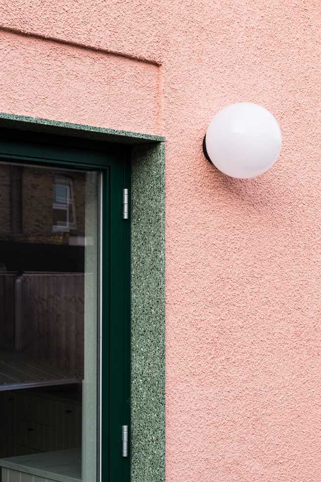 House with pink and green plaster. The colours break the connection with the traditional design