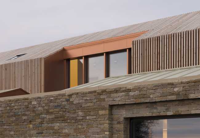 Juego de volúmenes tradicionales de un granero. Formas y paleta de materiales locales