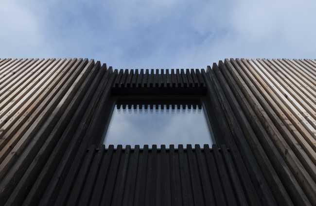Juego de volúmenes tradicionales de un granero. Formas y paleta de materiales locales