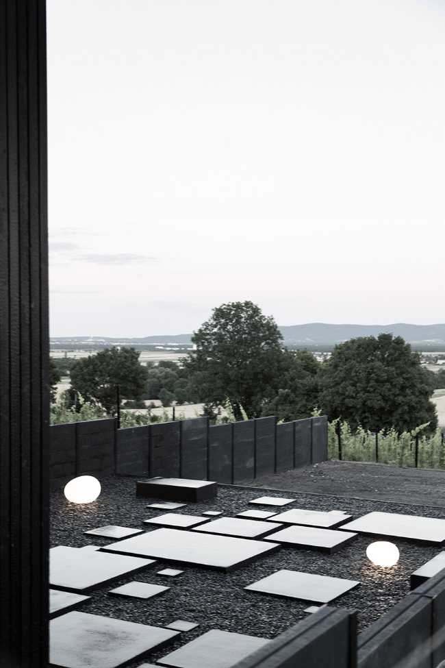 House on wine terraces. Wooden slats cover the structure like a velvety black veil
