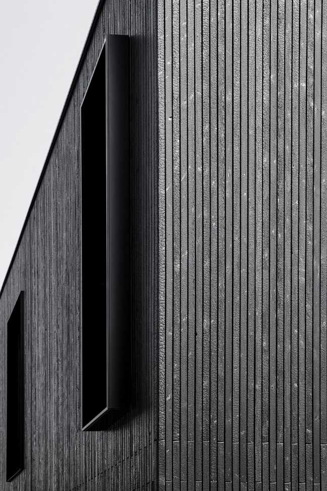 House on wine terraces. Wooden slats cover the structure like a velvety black veil