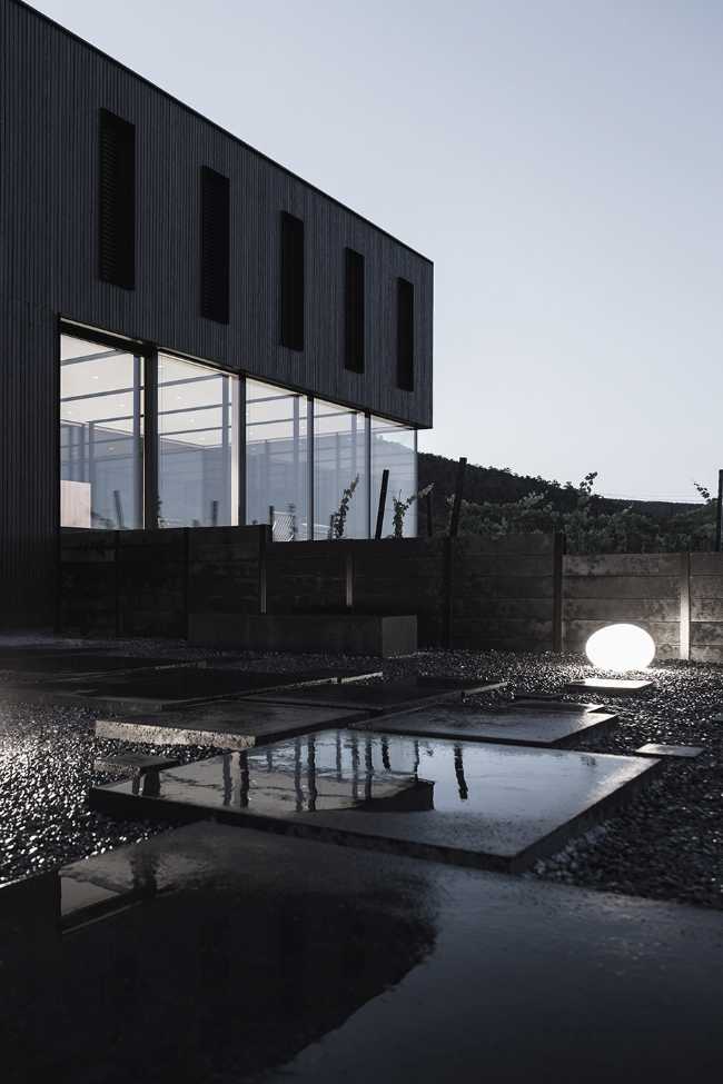 House on wine terraces. Wooden slats cover the structure like a velvety black veil