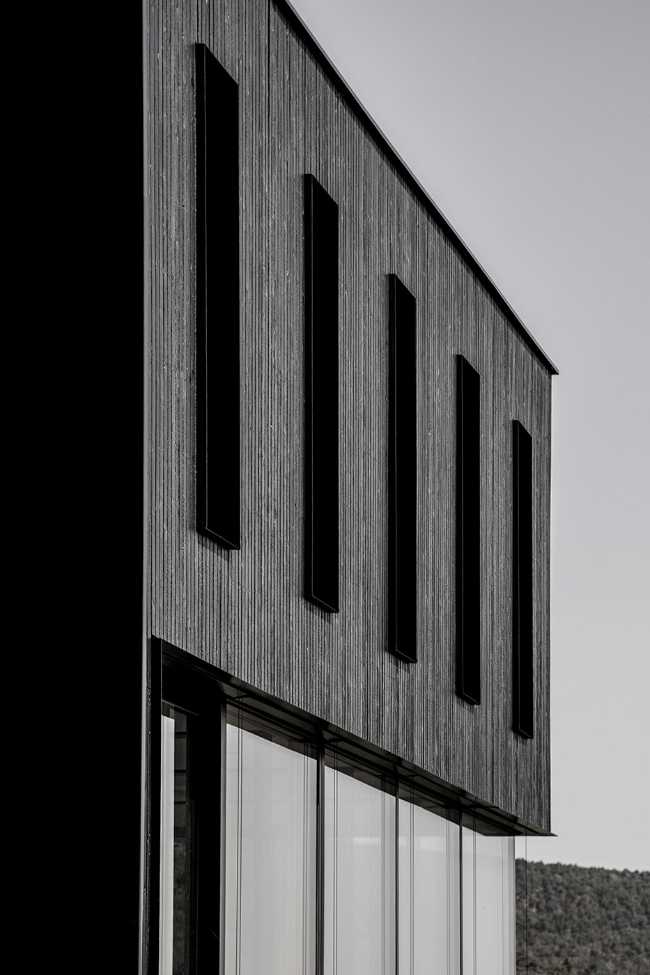 House on wine terraces. Wooden slats cover the structure like a velvety black veil