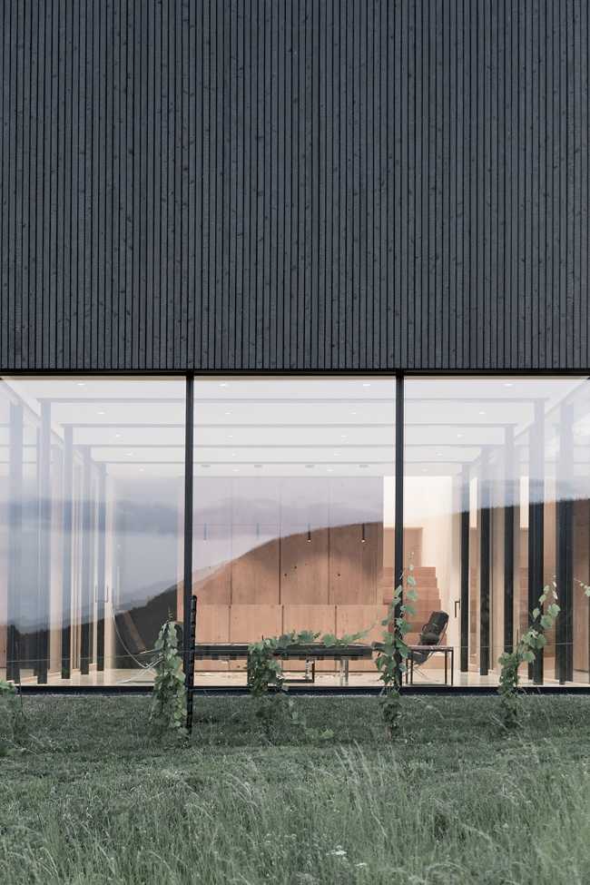 House on wine terraces. Wooden slats cover the structure like a velvety black veil