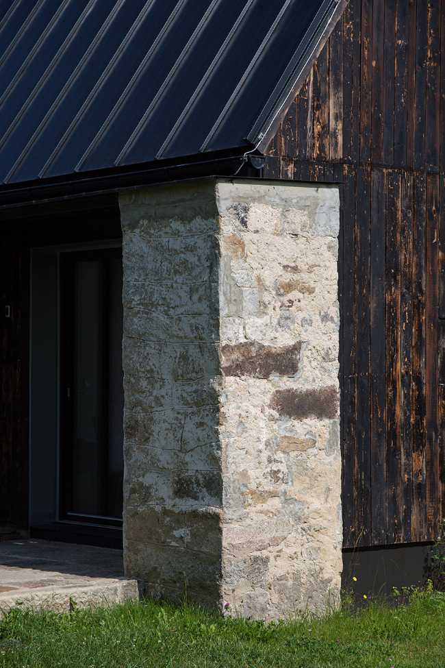 The old barn gives way to a small wooden house. Monumental granite walls preserved