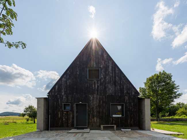 The old barn gives way to a small wooden house. Monumental granite walls preserved