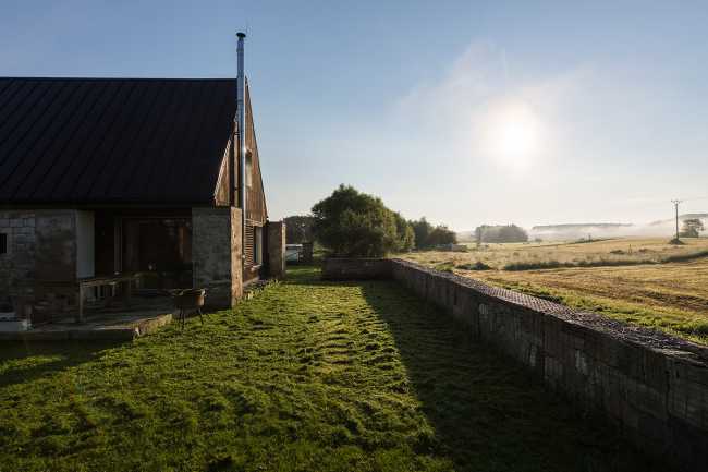 The old barn gives way to a small wooden house. Monumental granite walls preserved