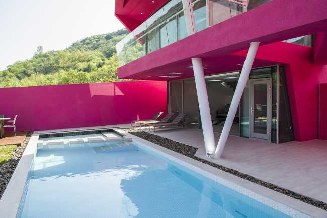 Villa de tonos rosas entre verdes colinas. Los muros circundantes enmarcan la espectacular vista