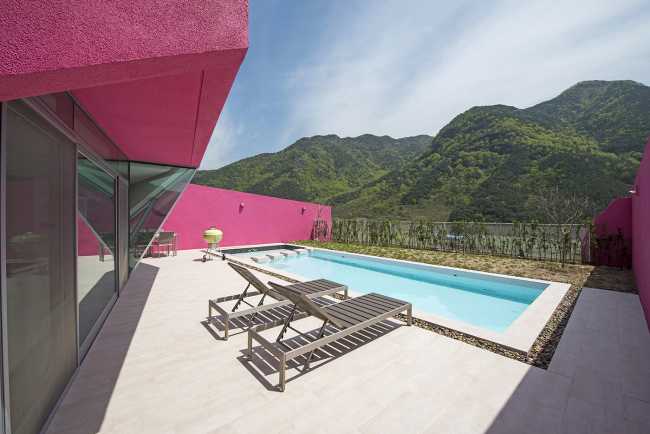 Villa de tonos rosas entre verdes colinas. Los muros circundantes enmarcan la espectacular vista