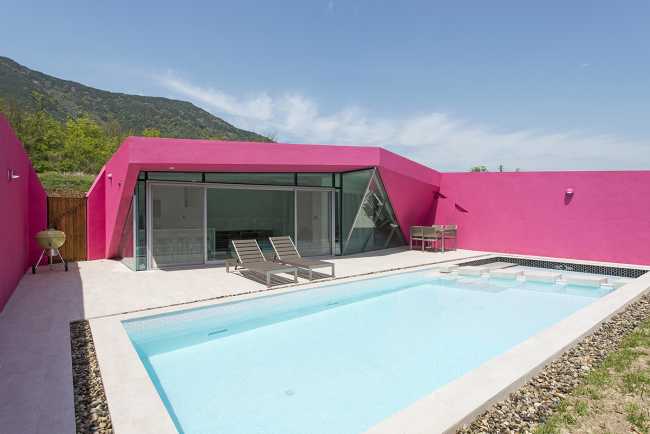 Villa de tonos rosas entre verdes colinas. Los muros circundantes enmarcan la espectacular vista