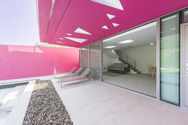 Villa de tonos rosas entre verdes colinas. Los muros circundantes enmarcan la espectacular vista