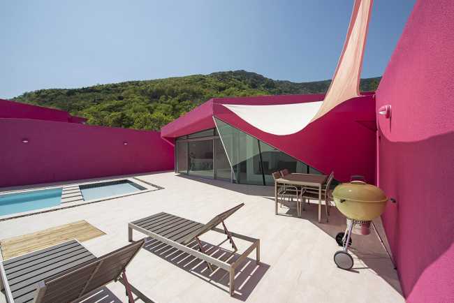 Villa de tonos rosas entre verdes colinas. Los muros circundantes enmarcan la espectacular vista