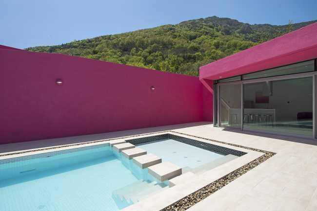 Villa de tonos rosas entre verdes colinas. Los muros circundantes enmarcan la espectacular vista