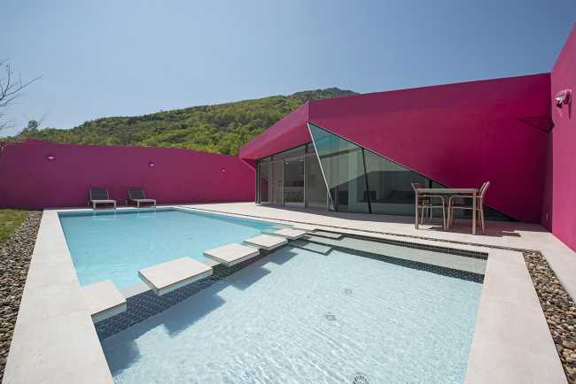 Villa de tonos rosas entre verdes colinas. Los muros circundantes enmarcan la espectacular vista