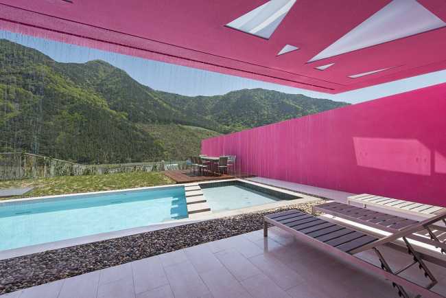 Villa de tonos rosas entre verdes colinas. Los muros circundantes enmarcan la espectacular vista