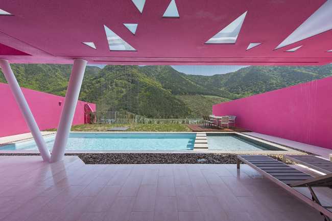 Villa de tonos rosas entre verdes colinas. Los muros circundantes enmarcan la espectacular vista