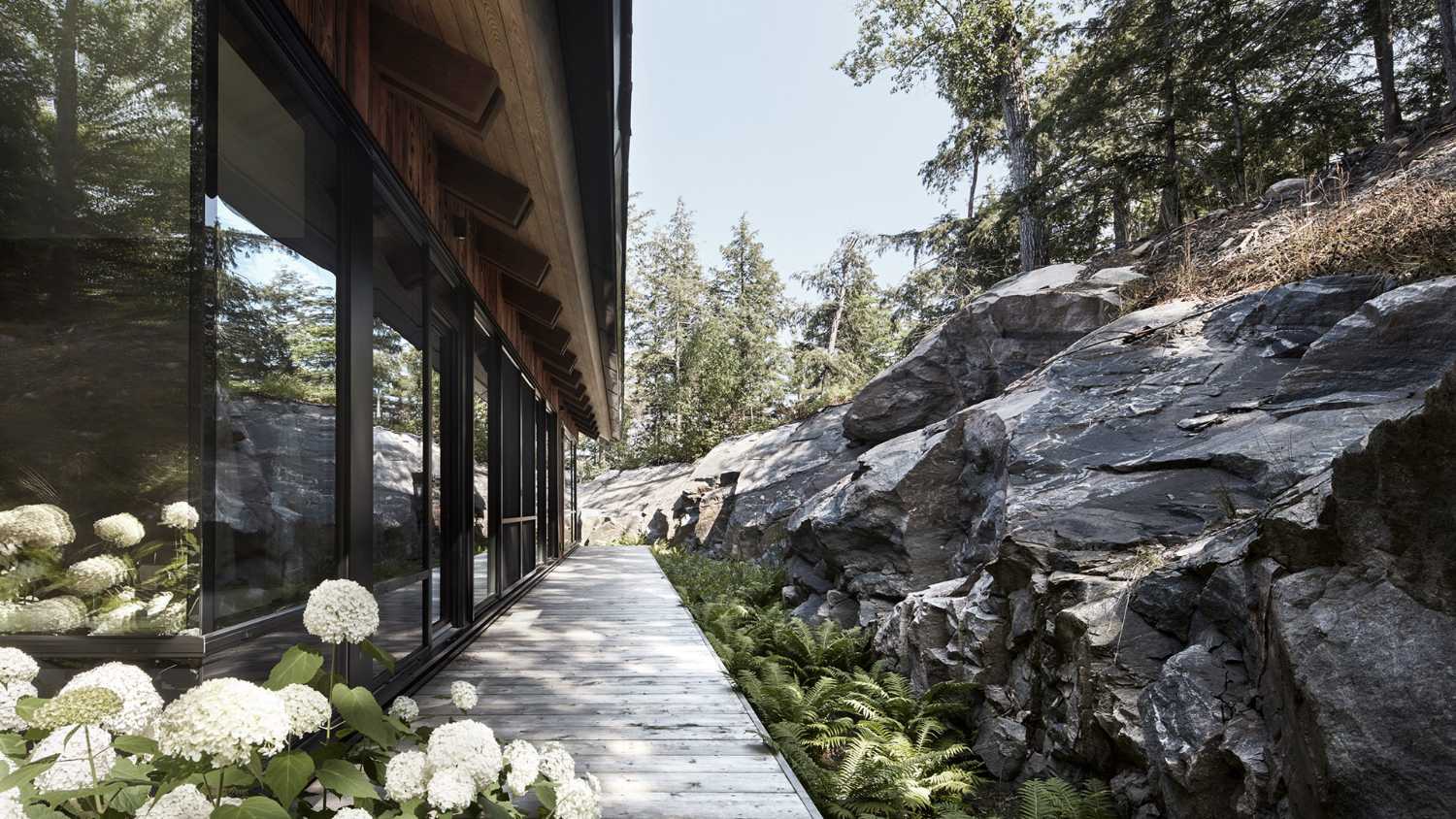 Un enclave rocoso alberga una cabaña de madera. Casa de botes a orillas de un lago