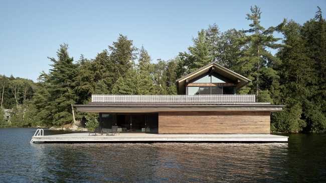 Une enclave rocheuse abrite un chalet en bois. Remise pour bateaux sur les rives d'un lac.