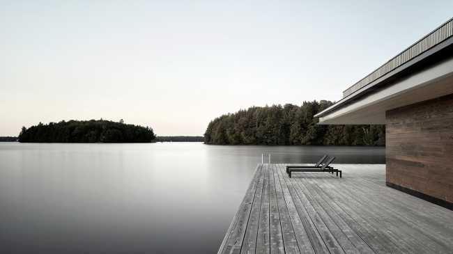 Une enclave rocheuse abrite un chalet en bois. Remise pour bateaux sur les rives d'un lac.