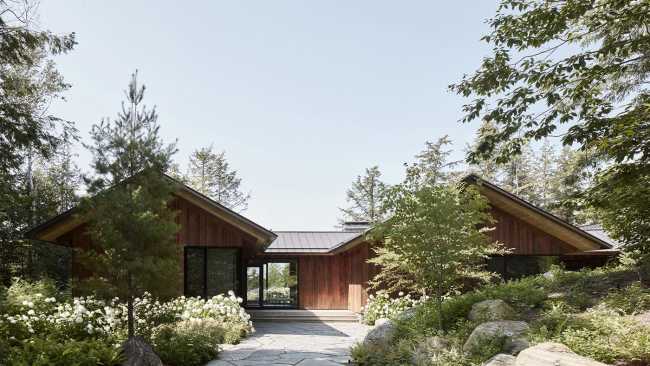 Une enclave rocheuse abrite un chalet en bois. Remise pour bateaux sur les rives d'un lac.