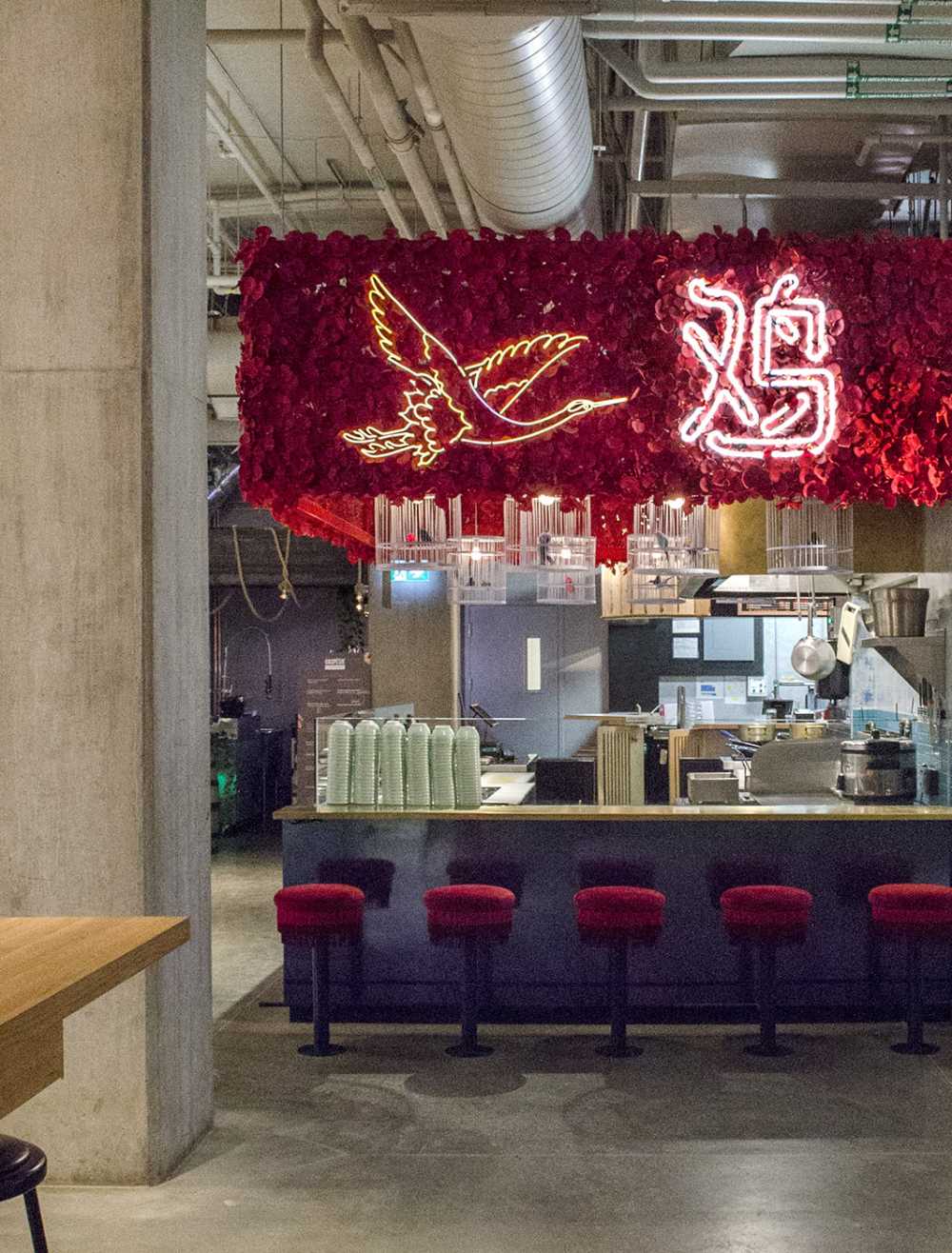 Ho Lee Chix. Fiori rossi e neon a forma di gru per una bancarella di street food