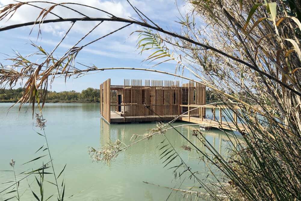 Suites de madera del Grand Cepage Hotel, como sofisticados nidos entre las cañas, se reflejan en el lago para una experiencia vital primordial