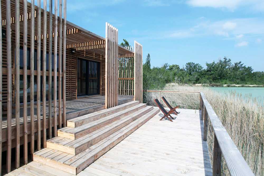 Suites de madera del Grand Cepage Hotel, como sofisticados nidos entre las cañas, se reflejan en el lago para una experiencia vital primordial