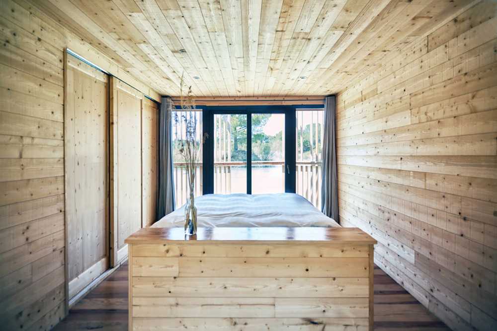 Suites de madera del Grand Cepage Hotel, como sofisticados nidos entre las cañas, se reflejan en el lago para una experiencia vital primordial